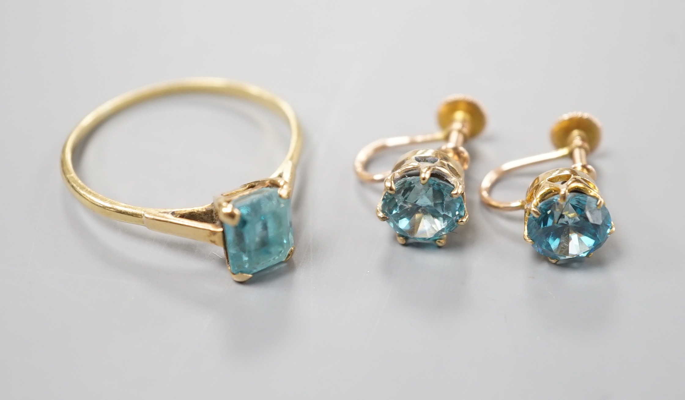 A pair of yellow metal and blue zircon ear clips and a yellow metal and paste set ring, gross weight 5 grams.